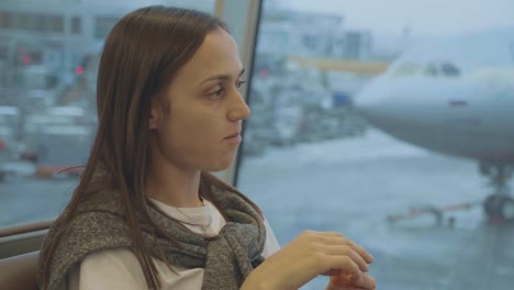 Joven-come-mandarina-en-el-aeropuerto-con-el-avión-en-el-fondo