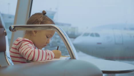 Niña-bebé-basándose-en-el-aeropuerto-con-el-avión-en-el-fondo