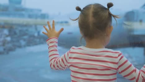 Little-child-girl-looks-out-of-window-on-airplane,-rear-wiew.