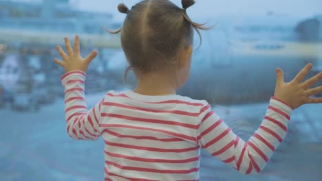 Little-child-girl-looks-out-of-window-on-airplane,-rear-wiew.