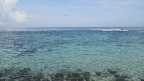 Avión-aterrizando-en-el-aeropuerto-de-Bali-la-isla-bajo-el-mar-con-olas-en-el-horizonte