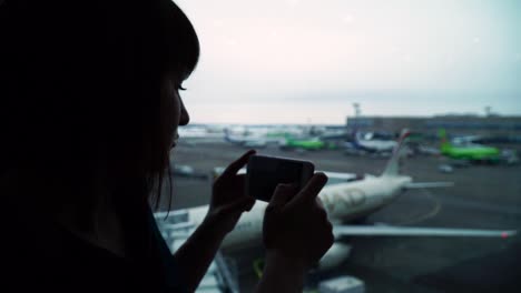 mujer-en-vuelo-de-espera-terminal-Aeropuerto-toma-fotos-en-un-teléfono-inteligente