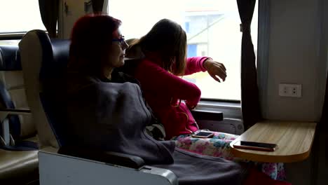 Two-women-are-sitting-on-the-train.-The-girl-takes-out-a-folding-table-from-the-armrest