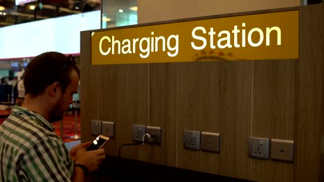 Un-hombre-está-cargando-un-smartphone-en-la-estación-de-carga-en-el-aeropuerto