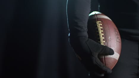 Sportsman-Holding-Football-Ball-on-Black-Background