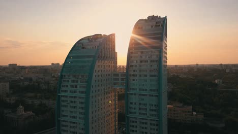 silhouette-of-double-tall-skyscrapper-with-bridge-between-them-against-the-sunset