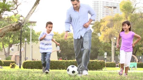 Vater-mit-Kindern-spielen-Fußball-im-Park-zusammen