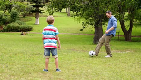 Padre-e-hijo-delante-y-hacia-atrás-fútbol-coleando-en-el-parque