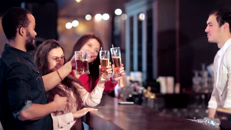 Cheerful-company-of-girls-and-a-guy-at-the-bar-lifts-up-a-glass-of-beer