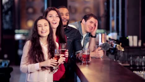 Group-of-girls-and-boys-at-the-bar-cheering-for-their-football-team