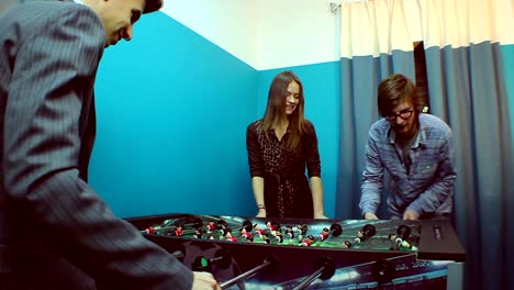 Two-men-woman-having-rest,-playing-table-football,-team-building