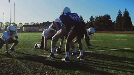 Football-players-running-a-play-on-the-field,-one-player-gets-tackled