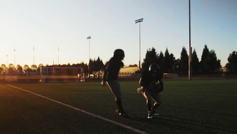 Two-football-players-bump-chests-and-high-five-after-a-good-play,-with-lens-flare