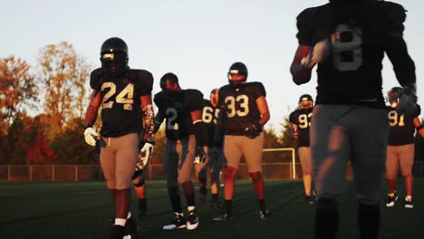 A-football-team-walks-onto-the-field-in-golden-light