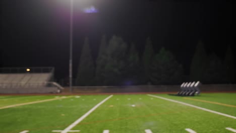 Two-football-players-running-a-drill-on-the-field-at-night