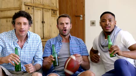 Friends-drinking-a-beer-and-watching-american-football-match-on-the-television