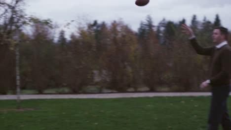 Father-and-son-passing-a-football-in-a-park-at-night,-slow-motion