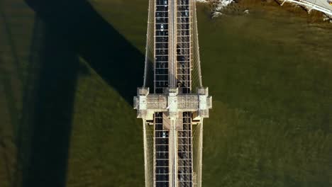 Top-aerial-view-of-the-Brooklyn-bridge-through-the-East-river.-Car-riding-to-Manhattan-in-New-York,-America