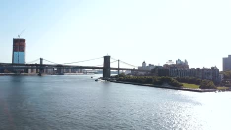 Aerial-view-of-Brooklyn-bridge-through-East-river-in-New-York,-America.-Drone-flying-over-water-in-Brooklyn-district