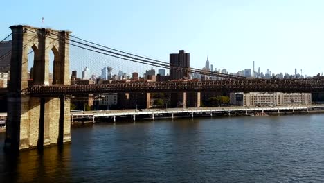 Aerial-view-of-the-Brooklyn-bridge-through-the-East-river-on-Manhattan,-New-York.-Drone-flying-over-the-traffic-road