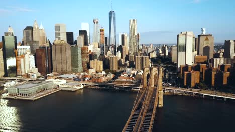 Aerial-view-of-the-Brooklyn-bridge-in-New-York,-USA,-going-to-the-Manhattan-district.-American-flag-waving-on-the-wind