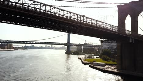 Vista-aérea-de-Nueva-York,-América.-Helicóptero-volando-bajo-el-puente-de-Brooklyn-a-Manhattan-bridge-a-través-de-este-río