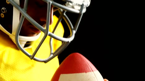 American-Football-Spieler-mit-Ball-vor-schwarzem-Hintergrund-4k