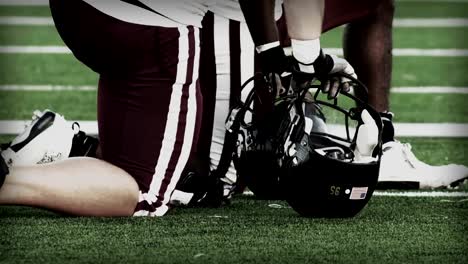 Close-up-of-two-football-players-taking-a-knee-on-the-field