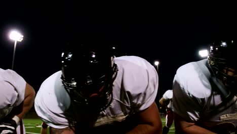 Close-up-dolly-shot-of-football-players-lined-up-at-the-line-before-the-snap