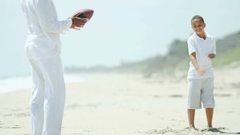 Son-and-dad-playing-American-football-on-beach