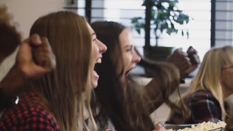 Gemischtrassig-Fans-feiern-Ziel-im-Fernsehen-zu-Hause.-Slow-Motion-Nahaufnahme.-Anhänger-ansehen-Fußballspiel-gemeinsam.-Emotion