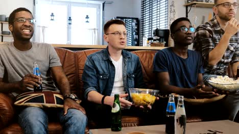 Afrikanische-amerikanische-männliche-Freunde-Sportübertragungen-im-Fernsehen.-Multi-ethnischen-geeky-Fans-konzentriert-und-ernsthaft-auf-Couch-mit-popcorn