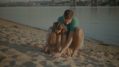 Kind-und-Vater-auf-der-Suche-nach-Muscheln-im-Sand-am-Strand