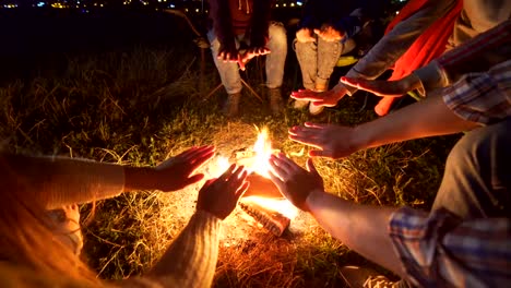 Die-fröhlichen-Menschen-sitzen-in-der-Nähe-am-Lagerfeuer.-Abend-Nacht