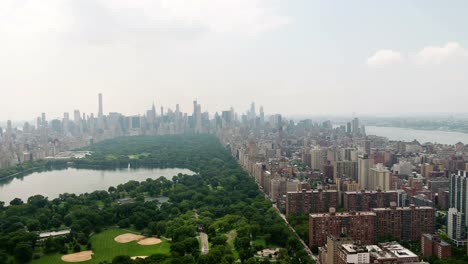 Central-Park-Antenne-voran-in-Richtung-Gebäude-über-grüne-Manhattan-New-York-City