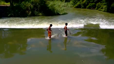 boys-walking-in-water-in-dam-with-fishes-after-catch-fish
