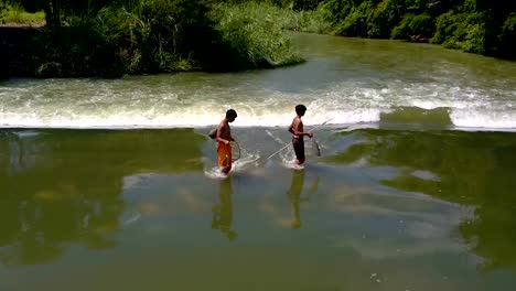 jungen,-die-zu-Fuß-in-Wasser-im-Stausee-mit-Fischen-nach-Fische-fangen