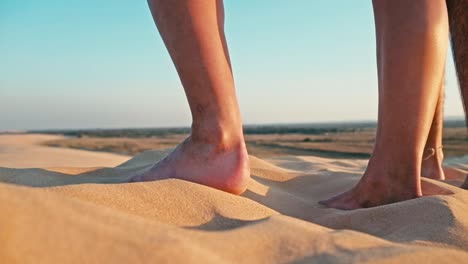 Nahaufnahme-der-Beine-einer-jungen-Frau-und-Mann-genießen-den-Sonnenuntergang-auf-dem-Gipfel-eines-einsamen-Sanddüne