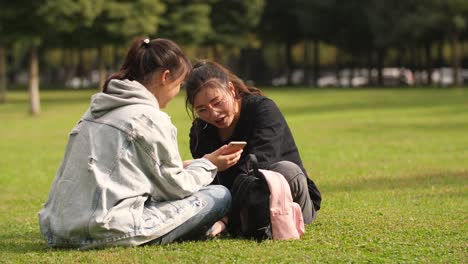 Zwei-asiatische-Studentin-mit-Handy-auf-dem-campus