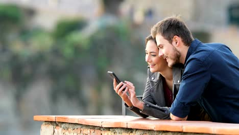 Happy-couple-checking-phone-content-in-a-balcony