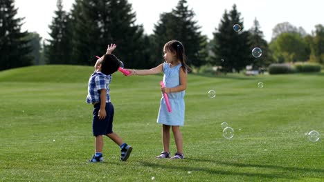 Entusiasmados-los-hermanos-asiáticos-divertirse-con-pompas-de-jabón