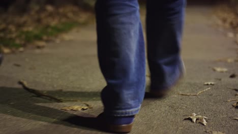 Two-pairs-of-feet-walking-down-a-sidewalk-at-night