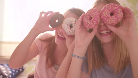 Teenager-Mädchen-mit-bunten-Donuts-auf-Ihre-Augen