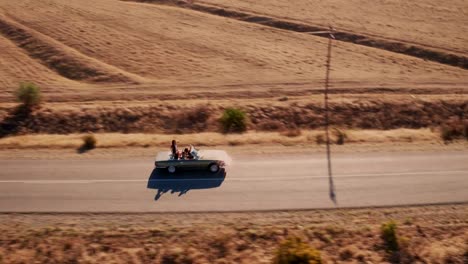 Hipster-friends-carefree-in-vintage-convertible-car-during-road-trip