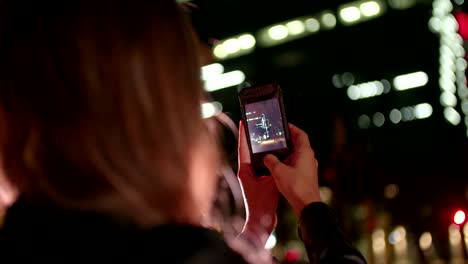 Hipster-girl-taking-a-night-shot-with-smartphone-in-town