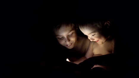 Two-young-brothers-playing-with-tablet-at-night.-4K