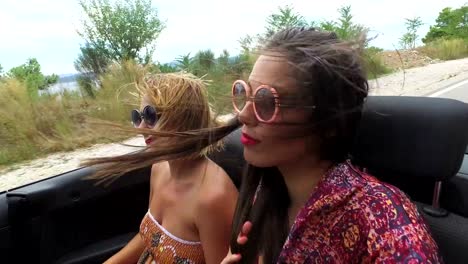 Two-carefree-girls-partying-while-riding-in-cabriolet