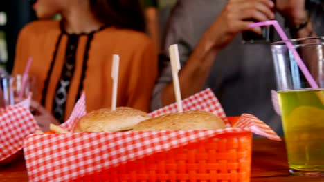 Friends-having-burger-and-drinks-in-restaurant