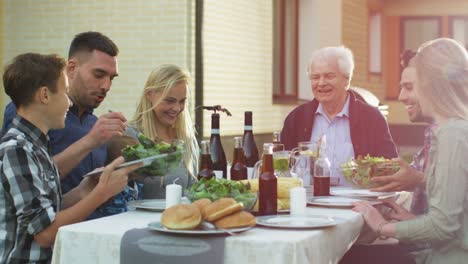 Grupo-de-gente-de-raza-mixta-divirtiéndose,-comunicándose-y-comiendo-en-la-cena-familiar-al-aire-libre