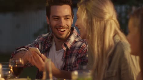 Hombre-guapo-con-teléfono-móvil-y-mostrar-contenido-a-su-novia-durante-la-cena-familiar.